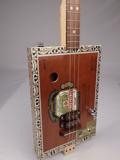Front view of a 3 string cigar box guitar made with a Queen B Fuente cigar box. This cigar box guitar is handmade by Mike Snowden of Snowden Guitars.