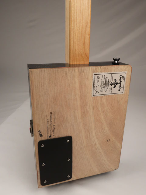 Back view of a cigar box guitar with Snowden logo sticker and plastic access panel. Handmade by Mike Snowden