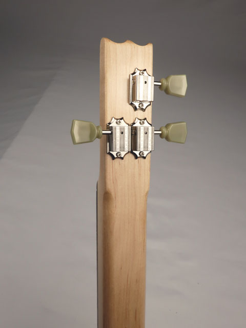 Back close-up of a cigar box guitar's tuning pegs on a gray background made by Mike Snowden.