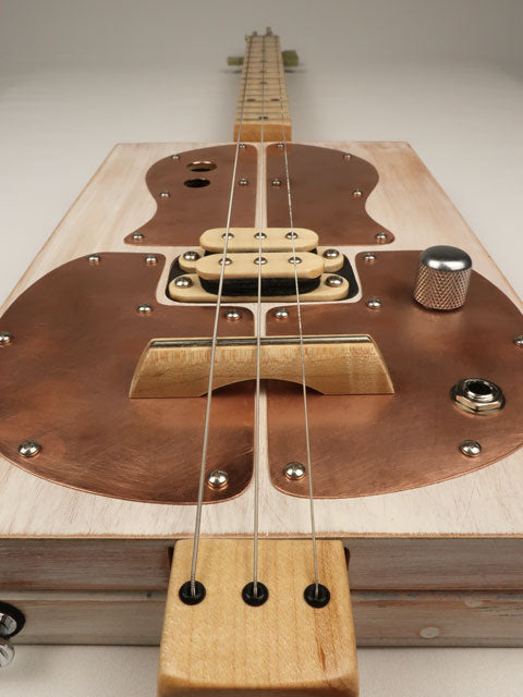 Cigar Box Guitar tilted view with copper pick guard and humbucker pickup. Made by Mike Snowden.