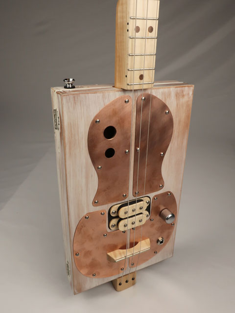 Cigar Box Guitar tilted view with copper pick guard and humbucker pickup. Made by Mike Snowden.