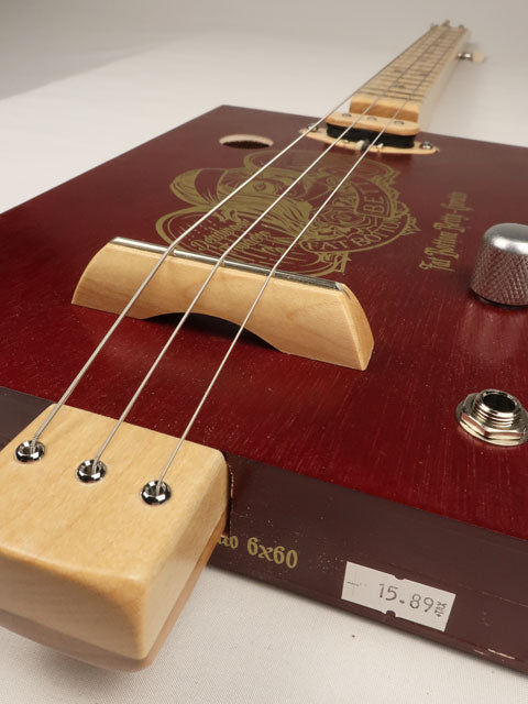 Close up view of a cigar  box guitar maple wood bridge. 3 String instrument made by Mike Snowden.