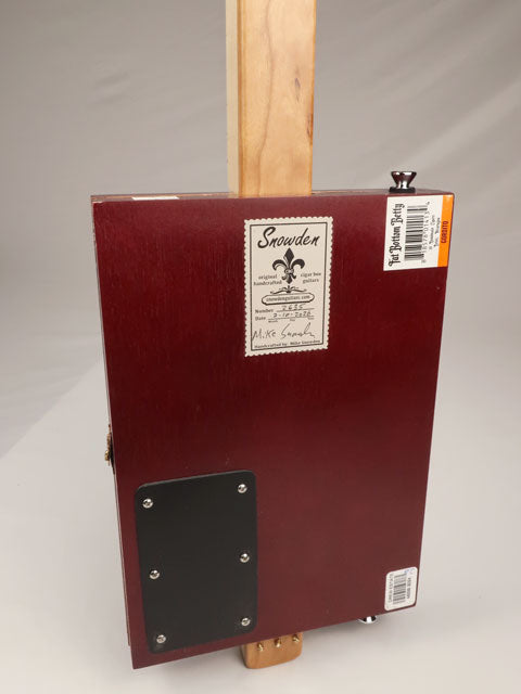 Back view of a red cigar box guitar with a red box and Snowden Guitars sticker. hand made by Mike Snowden.