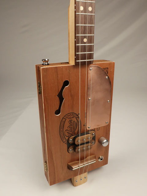 Cigar box guitar with copper pick guard and humbucker pickup. Handmade by Mike Snowden.