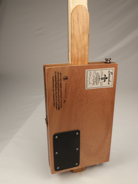 Back view of a cigar box guitar with Snowden Guitars logo and plastic access panel. 3 string instrument made by Mike Snowden.