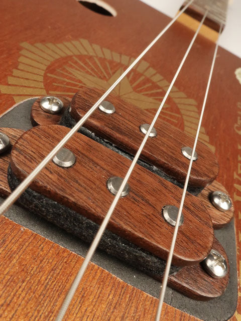 Close-up a 3 string cigar box guitar with a walnut humbucker pickup handmade by Mike Snowden. Made with walnut wood and magnets. 