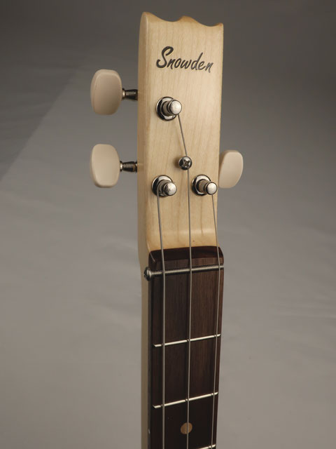 Close-up of a cigar box guitar guitar headstock with 'Snowden' branding on a gray background. Maple and walnut wood is used with this cigar box guitar.