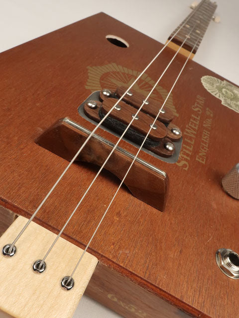 Close-up of a wooden cigar box guitar with a humbucker pickup. This cigar box guitar is handmade by Mike Snowden.