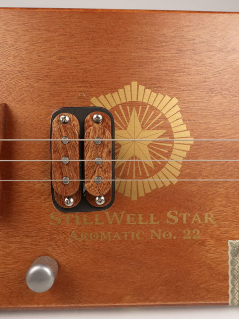 Close up front view of a 3 string cigar box guitar made with a StillWell Star cigar box. This cigar box guitar is made with a sapele fretboard and maple inlay by Mike Snowden of Snowden Guitars.
