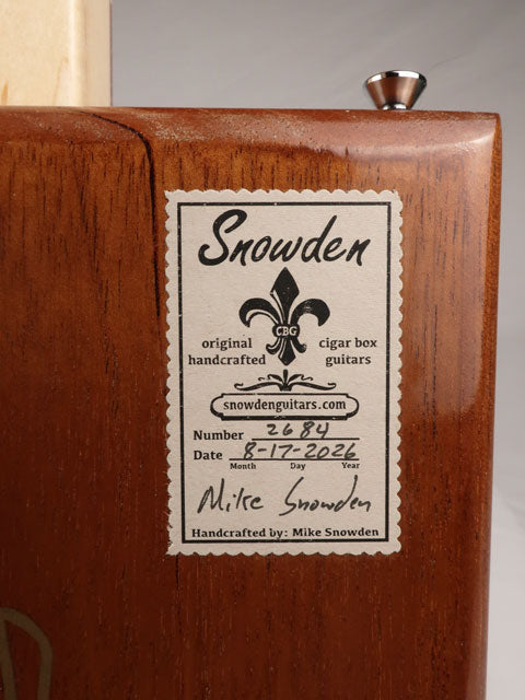 Back view of a cigar box guitar with a Snowden Guitars logo stating the date and number made by Mike Snowden of Snowden Guitars.