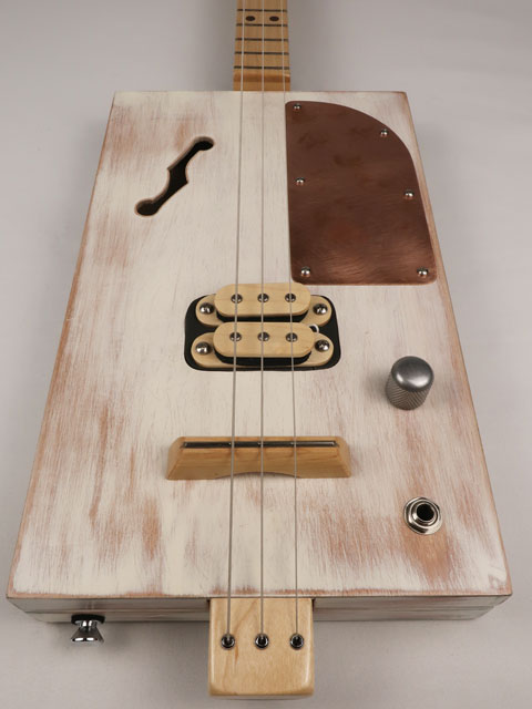 Front view of a 3 string cigar box guitar made with a humbucker pickup and copper pick guard. This cigar box guitar is handmade by Mike Snowden of Snowden Guitars.