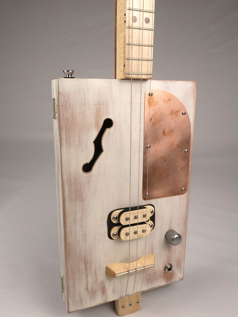 Front view of a 3 string cigar box guitar made with a humbucker pickup and copper pick guard. This cigar box guitar is handmade by Mike Snowden of Snowden Guitars.