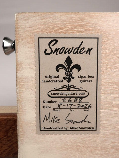 Back view of a cigar box guitar with Snowden Guitars logo on the back sticker. The sticker shows date and number of guitars handmade by Mike Snowden of Snowden Guitars.