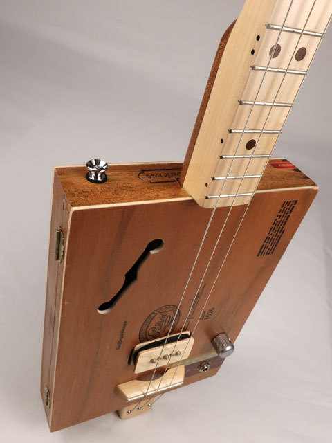 Tilted close up front view of cigar box guitar with a P90 pickup handmade by Mike Snowden. This cigar box guitar is made with a Padron cigar box and a maple neck.
