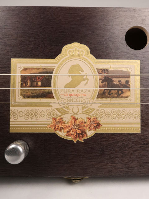 Close up front view of a 3 string cigar box guitar made with a Pura Raza cigar box. This cigar box guitar is made with walnut and maple with a single coil pickup by Mike Snowden of Snowden Guitars.