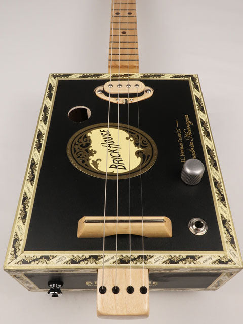 Front view of a 4 string cigar box guitar made with a Brick House cigar box. This cigar box guitar is made with a maple single coil pickup handmade Mike Snowden of Snowden Guitars.