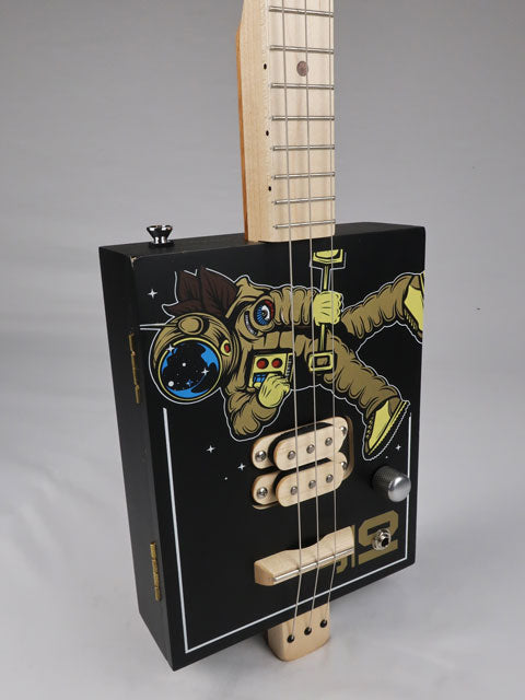 Front view of a 3 string cigar box guitar with an astronaut space suit on the front. Maple neck and maple humbucker pickup handmade by Mike Snowden of Snowden Guitars.
