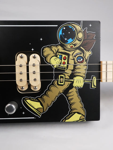 Front view of a 3 string cigar box guitar with an astronaut space suit on the front. Maple neck and maple humbucker pickup handmade by Mike Snowden of Snowden Guitars.