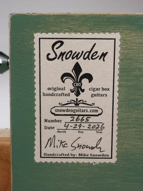 Back view of a cigar box guitar with a Snowden Guitars sticker on the back. This sticker tells the date the cigar box guitar was made and the number made. 