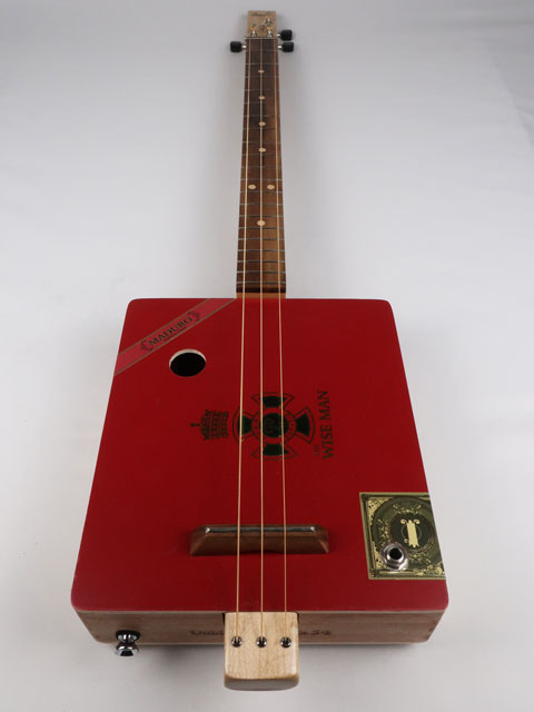 Front view of a cigar box guitar handmade by Mike Snowden. This red 3 string cigar box guitar has a walnut fretboard and maple neck.