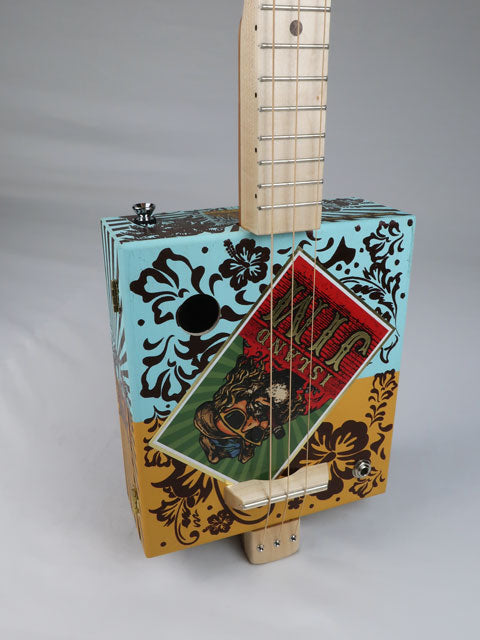Front view of a cigar box guitar handmade by Mike Snowden. 3 string cigar box guitar with an Island Jim logo on the front.
