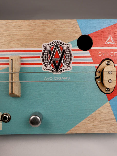 Front view of a 2 string cigar box guitar made with an AVO cigar box. Maple bridge and maple single coil pickup. Handmade by Mike Snowden of Snowden Guitars. 