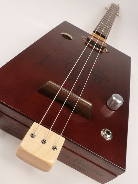 Front tilted view of a 3 string cigar box guitar made with a New Orleans Cigar Factory cigar box handmade by Mike Snowden of Snowden Guitars.