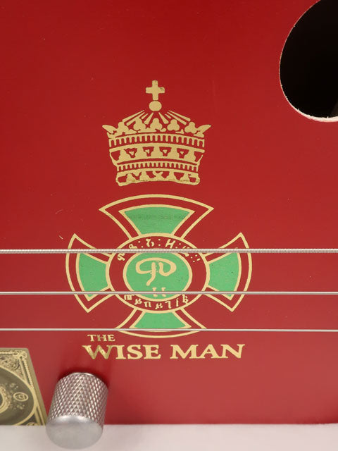 Close up view of The Wise Man 3 string cigar box guitar handmade by Mike Snowden. This cigar box is made with a red cigar box with The Wise Man printed on the front.