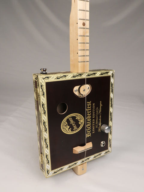 Front tilted view of a one string diddly bow cigar box guitar cbg made with a Bricktoberfest cigar box. Handmade by Mike Snowden of Snowden Guitars.