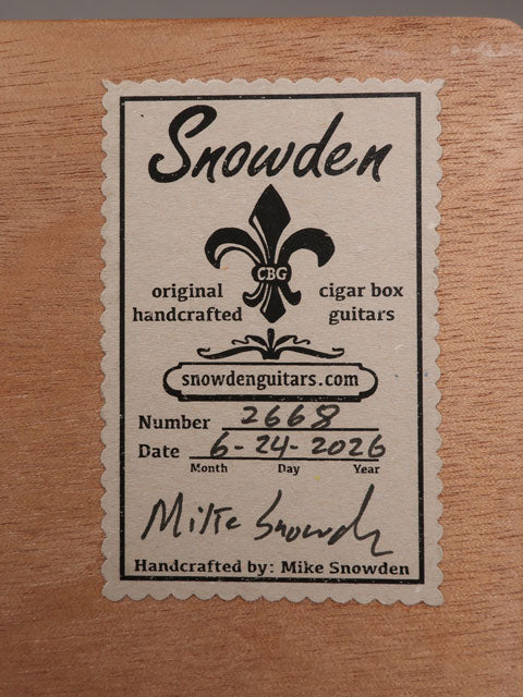 Back view of a cigar box guitar label. The label shows the maker, date and how many guitars made by Mike Snowden of Snowden Guitars.