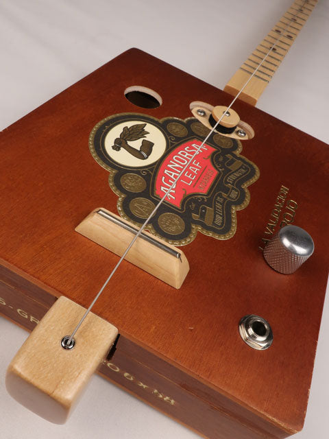 Front view of a single string diddly bow cigar box guitar made with a Aganorsa Leaf cigar box. Handmade by Mike Snowden of Snowden Guitars.