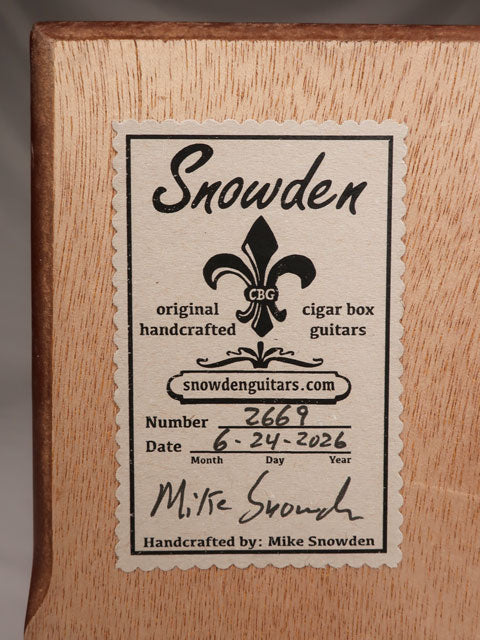 Back view of a cigar box guitar with Snowden Guitars label on the back. The tag shows the builder date and how many guitars made by Mike Snowden of Snowden Guitars.