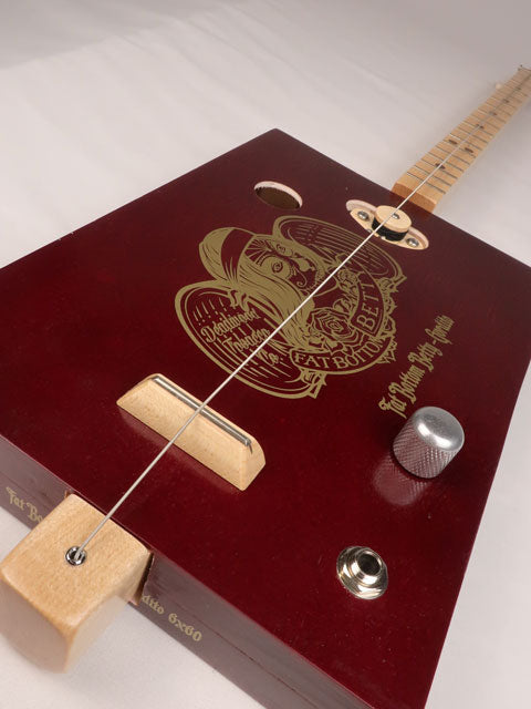 Front tilted view of a one string diddly bow cigar box guitar made with a Fat Bottom Betty cigar box. Handmade by Mike Snowden of Snowden Guitars.