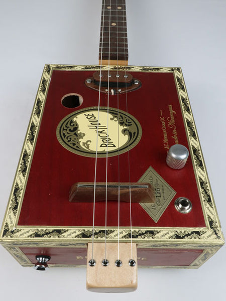 Front view of a 4 string cigar box guitar made with a Brick House cigar box and a walnut single coil pickup. This red cigar box guitar is handmade by Mike Snowden.