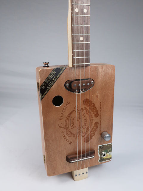 Tilted side view of a 4 string Cigar Box Guitar handmade by Mike Snowden. This cigar box guitar is made from a Jaime Garcia cigar box with a walnut single coil pickup.