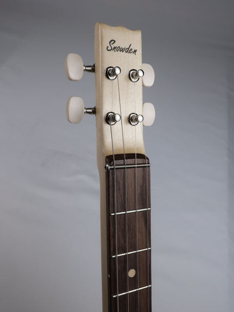 Close up view of a cigar box guitar headstock with a Snowden Guitars logo in black type of a maple neck with walnut fretboard.