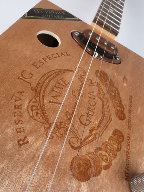 Close-up front view of a Cigar Box Guitar handmade by Mike Snowden. This cigar box guitar is made from a Jaime Garcia cigar box with a walnut single coil pickup.