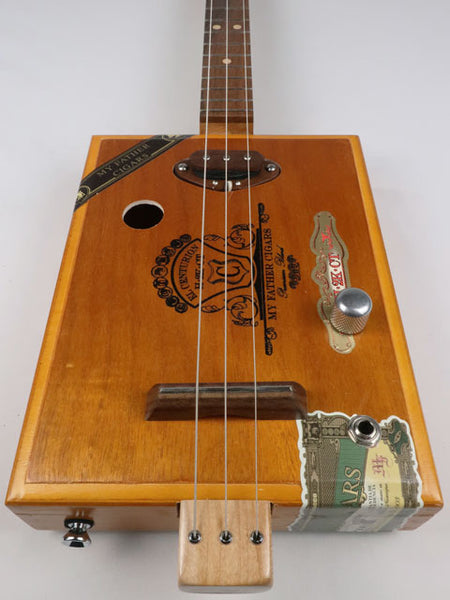 Front view of a 3 string Cigar Box Guitar made with a walnut single coil pickup. This cigar box guitar was handmade by Mike Snowden of Snowden Guitars.