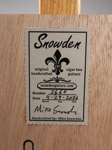 Back view of a cigar box guitar sticker with Snowden Guitars logo. The ticker tells  the date and number of this cigar box guitar handmade by Mike Snowden of Snowden Guitars.