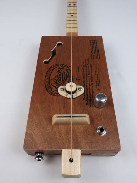 Front view of a one string diddly bow cigar box guitar with a maple single coil pickup and a maple neck and frets. This cigar box guitar is handmade by Mike Snowden.