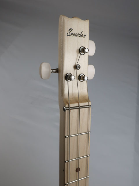 Close up of a 3 string cigar box guitar head stock with a Snowden Guitars logo on the front. This maple neck cigar box guitar has a maple fretboard with frets and walnut inlay.