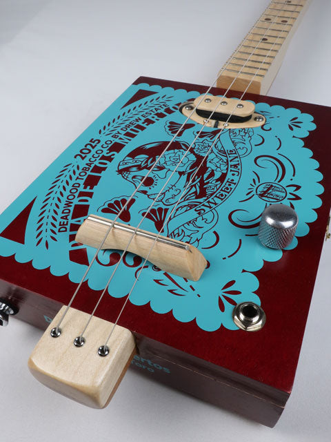 Angle view of a 3 string cigar box guitar head stock with a Snowden Guitars logo on the front. This maple neck cigar box guitar has a maple fretboard with frets and walnut inlay.