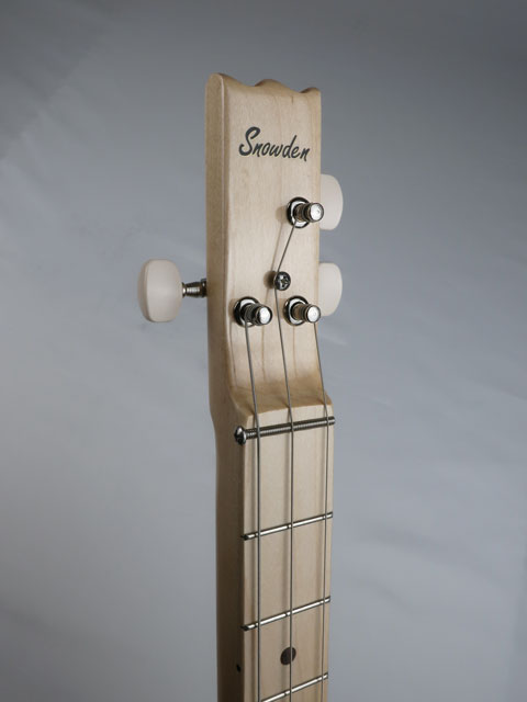 Close-up view of a 3 string cigar box guitar headstock with Snowden guitars logo on the front. This maple neck and maple fretboard with walnut inlay is handmade by Mike Snowden of Snowden guitars.