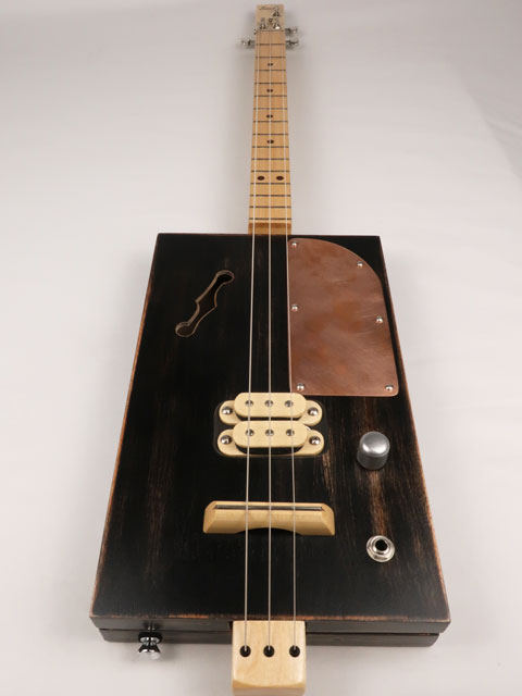 Front view of a 3 string cigar box guitar with a copper pick guard and maple humbucker. This cigar box guitar is handmade by Mike Snowden of Snowden Guitars.