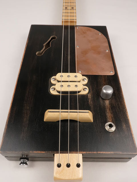 Front view of a 3 string cigar box guitar with a copper pick guard and maple humbucker. This cigar box guitar is handmade by Mike Snowden of Snowden Guitars.