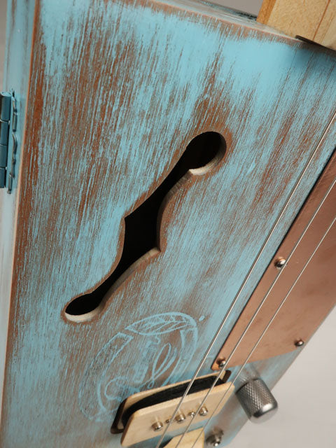 Close-up view blue cigar box guitar f hole made by mike snowden.